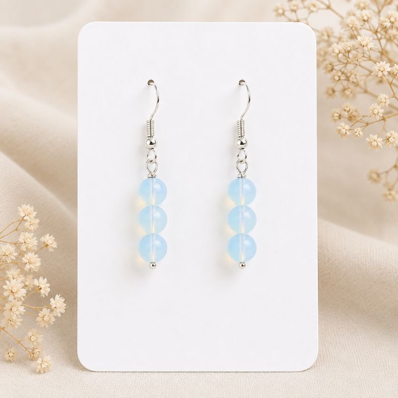 Moonlit Opalite Drop Earrings featuring three luminous Opalite beads on silver-tone hooks displayed on a white jewelry card.